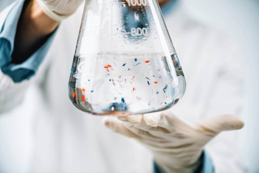 Scientist holding a bottle of glass full of microplastics